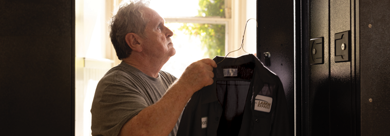 Male employee getting ready for the workday, grabbing his rental uniform work shirt from his locker delivered by uniform services.